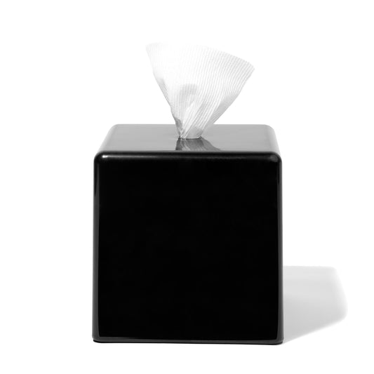 Black square tissue box with tissues peeking out on a white background