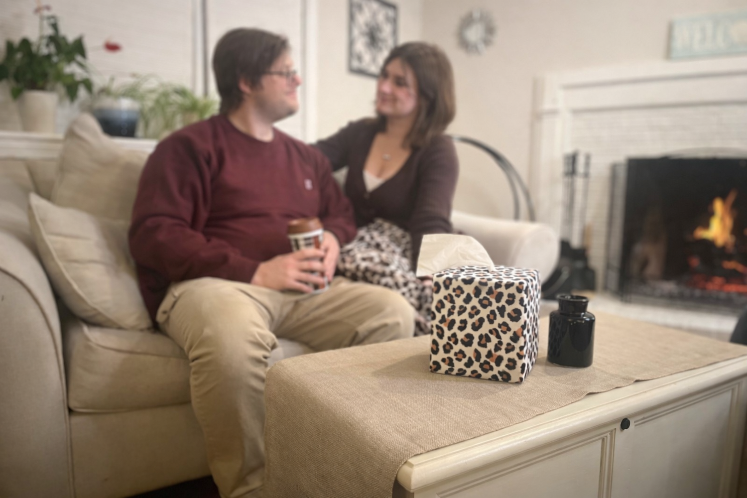 Man and woman sitting on a couch in a living room with a fireplace. Modern Leopard AchooBox on coffee table
