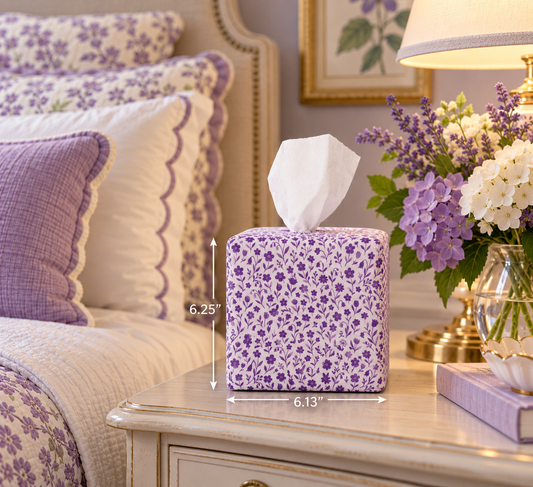 A purple and white floral tissue box cover sits on a bedside table in a bedroom setting, with dimension lines showing its height as 6.25 inches and width as 6.13 inches.