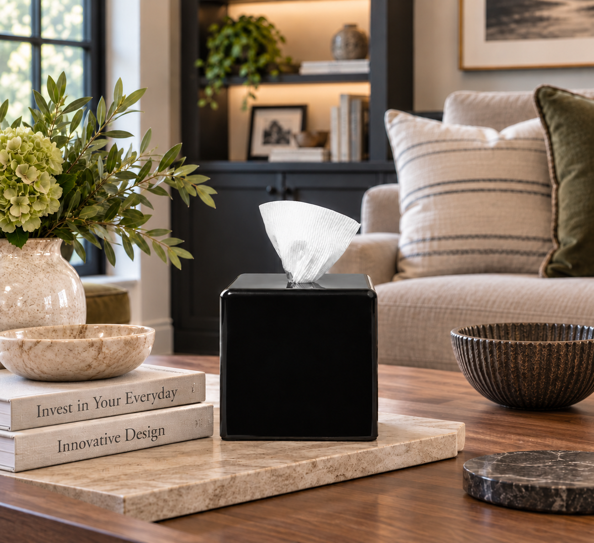 bold black achoobox sitting on a coffee table next to books and a plant
