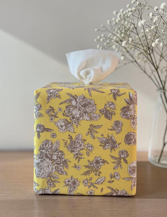 Buttercup Garden Toile AchooBox has a yellow background and a brown floral toile de Jouy pattern, sitting on a wooden table with baby's breath flowers in the background.