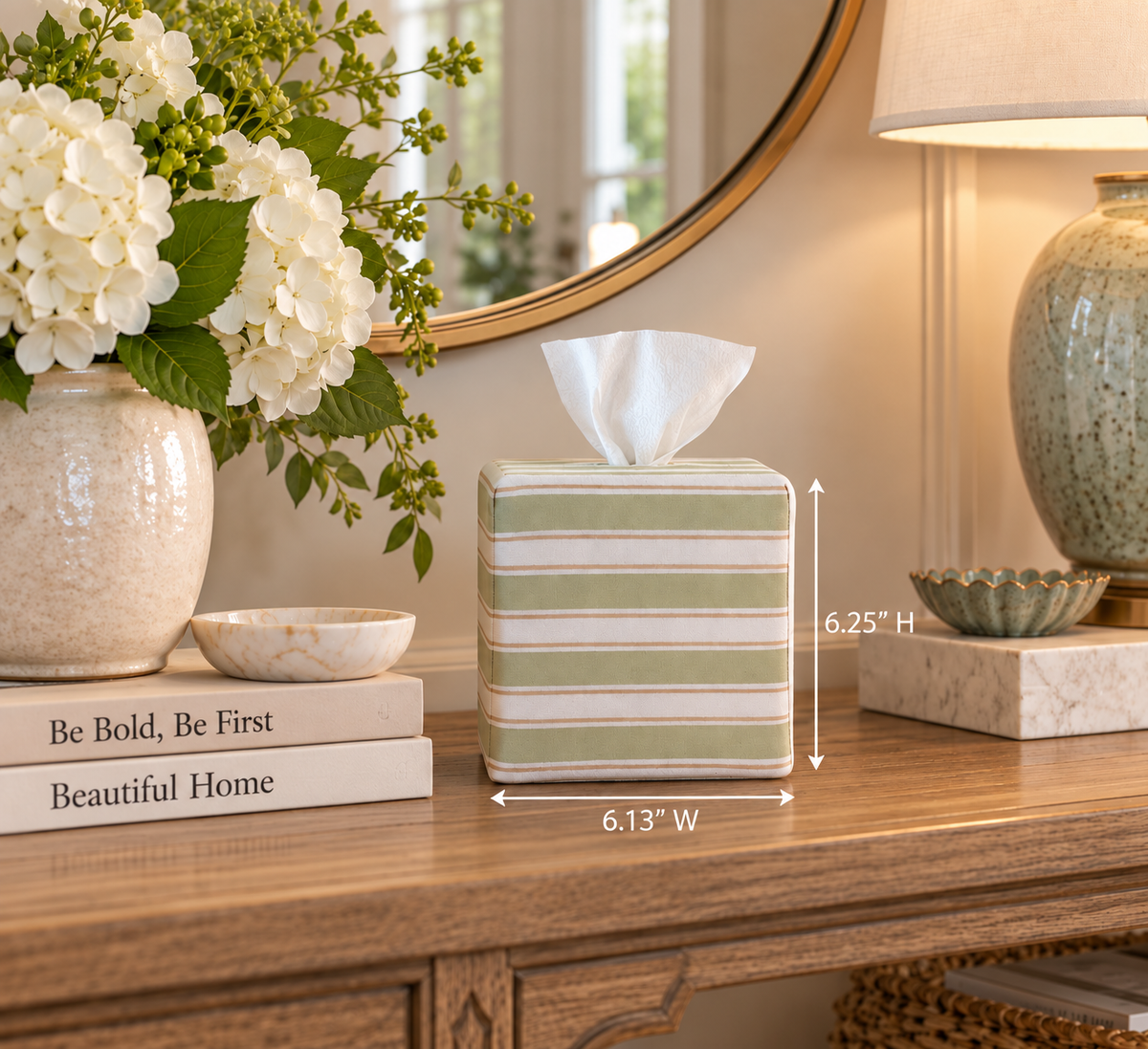 Arbor Stripe AchooBox with a striped pattern in sage green, cream, and white, shown on a wooden console table in a styled home interior. White dimension arrows overlay the product showing dimensions as 6.13" wide and 6.25" tall.