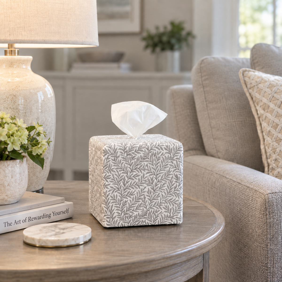 Harbor Mist Leaf AchooBox tissue box on round gray end table in a living room with book The Art of Rewarding Yourself