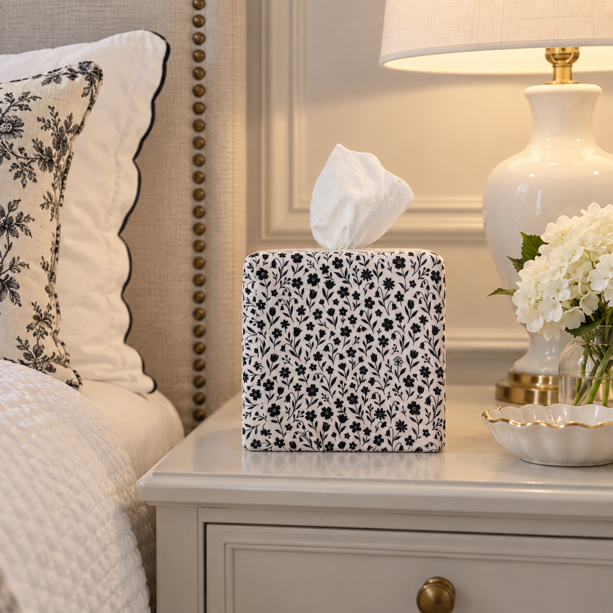 Midnight Bloom AchooBox Core Set has a navy floral pattern on a white background and sits on a light gray bedside table next to a white ceramic lamp and flowers.