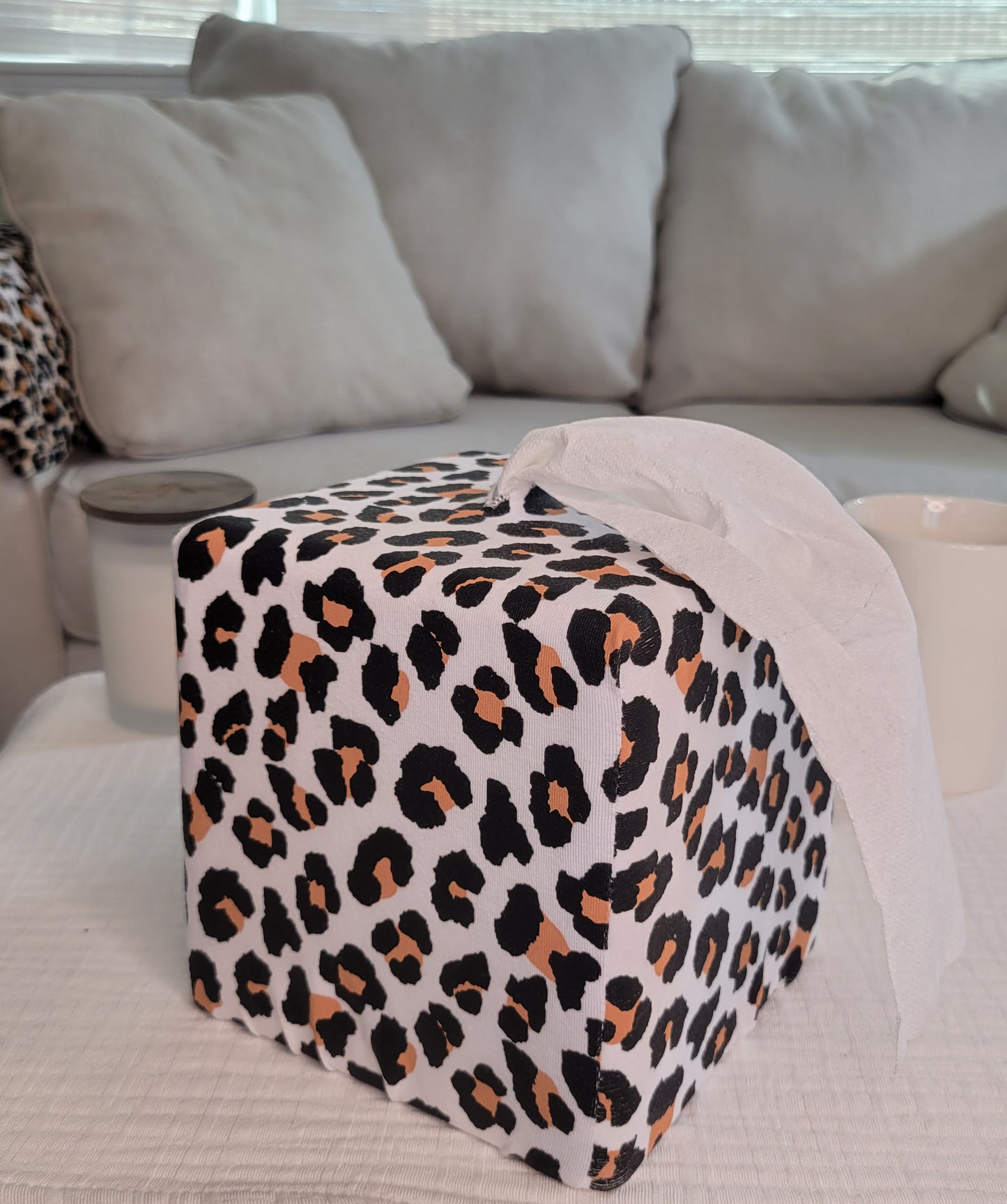Modern Leopard printed AchooBox Rolled Tissue Dispenser on coffee table with long tail of bath tissue dispensed from the top